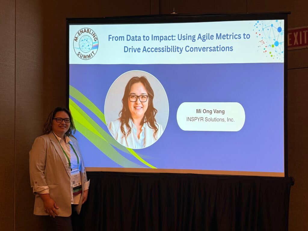 Mi Ong standing in front of her title slide presentation at M-Enabling 2025.  From Data to Impact: Using Agile Metrics to Drive Accessibility Conversations
